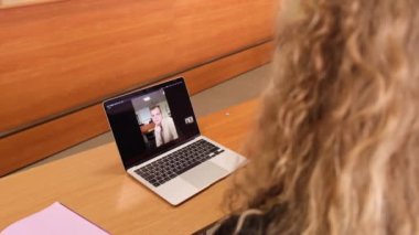 Kız, oğlanla dizüstü bilgisayardaki bir video görüşmesinde işaret diliyle iletişim kuruyor..