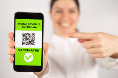 Aşılama hakkında qr kodlu akıllı telefon gösteren bir kadın.