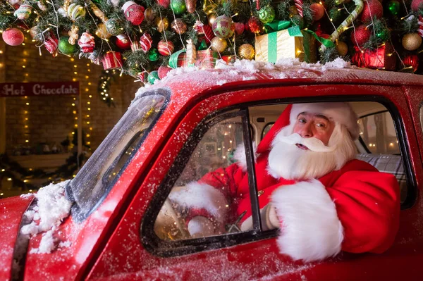 Retrato de Papai Noel dirigindo um carro carregado com uma árvore de Natal e presentes — Fotografia de Stock