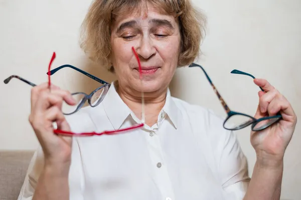 Una anciana caucásica elige gafas de su colección casera — Foto de Stock