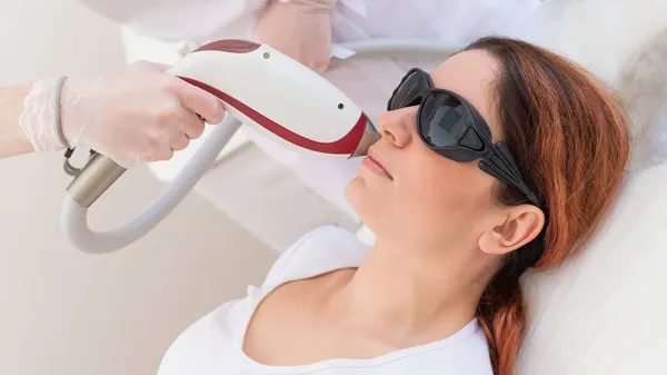 Zbliżenie depilacji laserowej na kobiecej twarzy. Lekarz usuwa niechciane włosy z ust pacjenta za pomocą urządzenia elektrycznego. — Zdjęcie stockowe