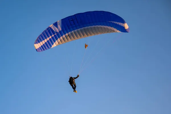 Silhouette di un uomo su un parapendio che vola nel cielo blu. — Foto Stock