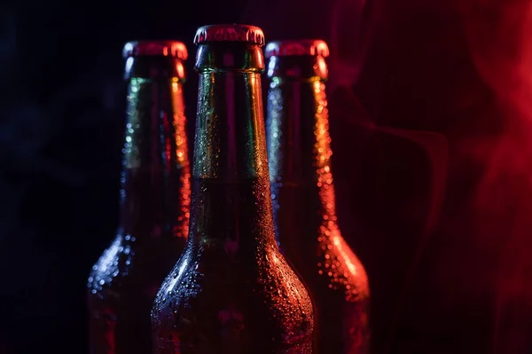 Tres botellas de cerveza en una niebla azul-rosa. — Foto de Stock