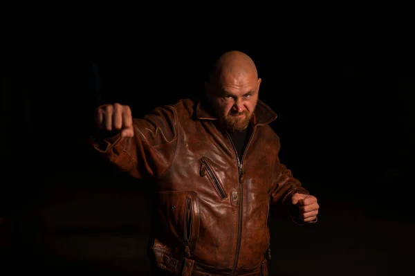 Deri ceketli kızgın bir adam karanlıkta saldırıyor.. — Stok fotoğraf