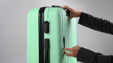 Bir kadın beyaz arka planda kırık bir bavulu gösteriyor. Uçuş sırasında hasarlı bagaj..