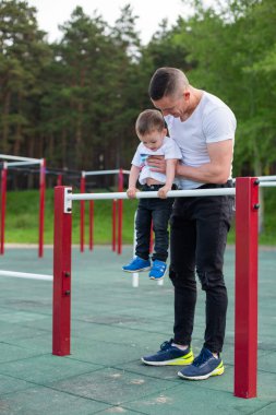 Kafkasyalı bir adam oyun parkındaki düzensiz barlarda bir çocuğu eğitiyor. Baba ve oğul açık hava sporlarına gider..