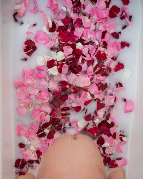 El hombre toma un baño con leche y pétalos de rosa. —  Fotos de Stock