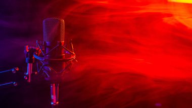 Siyah arka planda kırmızı dumanlı profesyonel mikrofon..