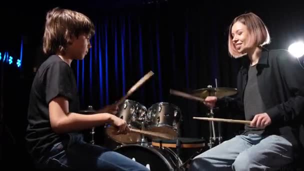 Jonge blanke vrouw leert een jongen drummen in de studio op een zwarte achtergrond. Muziekschool student — Stockvideo