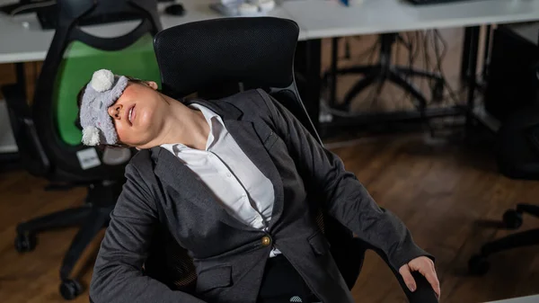 Mujer de negocios con una máscara con los ojos vendados dormida en la oficina. Empleado agotado en el lugar de trabajo —  Fotos de Stock