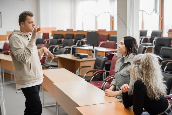 两个女孩和一个男人在用手语说话。三个聋哑学生在一所大学的教室里聊天. — 图库照片