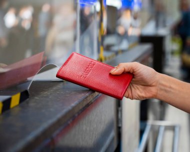 Kimliği belirsiz bir kadın havaalanı gişesinde pasaportunu veriyor..