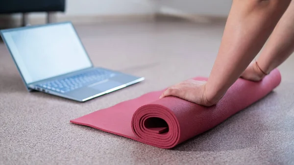 上完网上健身课后，胖胖的年轻女子会把运动垫叠起来 — 图库照片