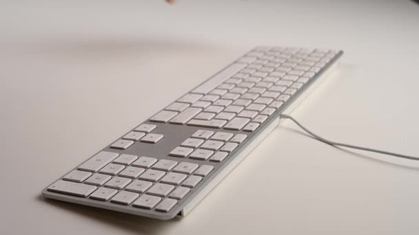 Eine Frau staubt eine weiße Tastatur auf einem weißen Arbeitstisch ab. — Stockvideo