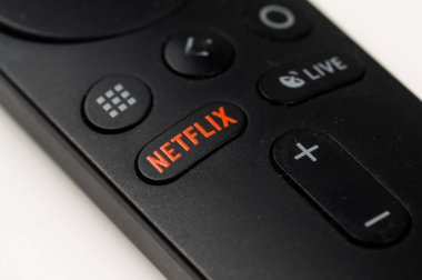 Beyaz masadaki netflix düğmesi ile siyah bir uzaktan kumandanın yakın plan görüntüsü.