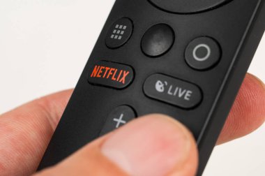 Rusya, Novosibirsk 10.11.2021: Beyaz bir masanın üzerinde netflix tuşu ile siyah bir uzaktan kumanda tutan bir adama yakın çekim.