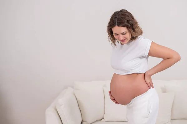 Těhotná žena drží břicho a dolní část zad. — Stock fotografie