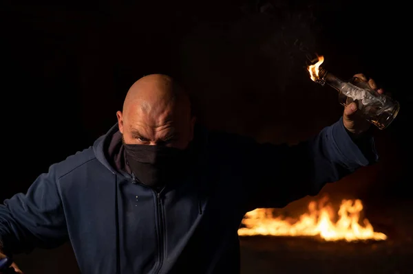 Maskeli bir adam yanan bir şişe tutuyor. Molotof kokteyli. — Stok fotoğraf