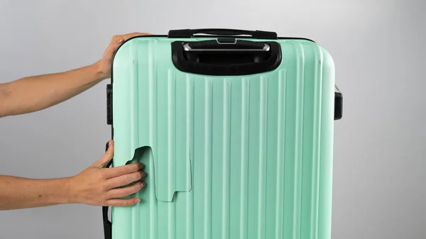 一个女人在白色的背景上展示一个破手提箱.飞行过程中行李损坏. — 图库照片