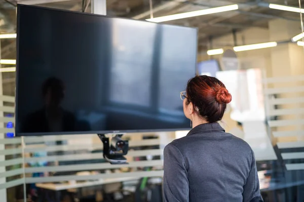 Mujer de negocios mirando la pantalla de TV en la oficina. — Foto de Stock