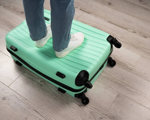 Femme debout avec ses pieds sur une valise. — Photo