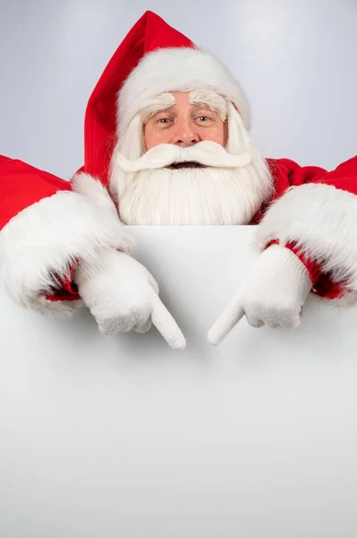 Święty Mikołaj wskazuje na białe miejsce do kopiowania. Reklama. Wesołych Świąt. — Zdjęcie stockowe