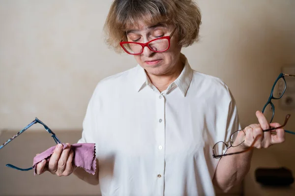 En äldre kaukasisk kvinna väljer glasögon från sin hemsamling — Stockfoto