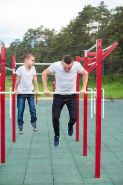Kafkasyalı bir adam oyun parkındaki düzensiz barlarda bir çocuğu eğitiyor. Baba ve oğul açık hava sporlarına gider..