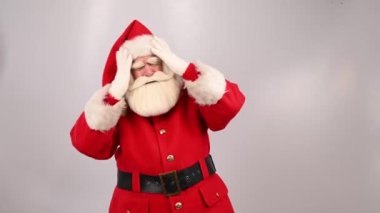 Üzgün Noel Baba kafasını beyaz bir arka planda tutuyor..