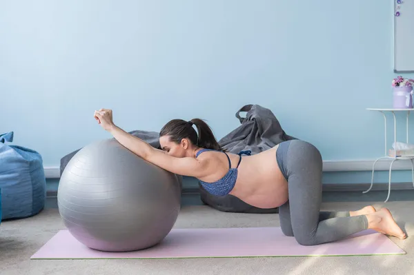 Mujer europea embarazada realiza ejercicios con pelota de fitness. La madre embarazada está haciendo yoga en el tercer trimestre. Chica en el aula en preparación para el parto . —  Fotos de Stock