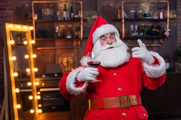 Santa Claus se sklenkou červeného vína přeje veselé Vánoce a říká přípitek — Stock fotografie