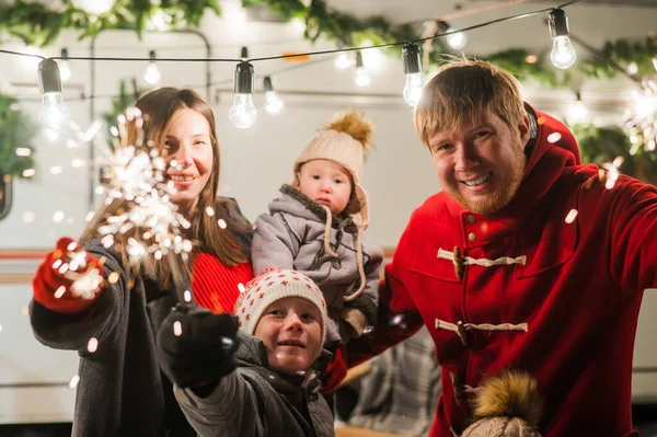 Lycklig familj firar jul i naturen och håller tomtebloss. Föräldrar med tre söner reser i en skåpbil. — Stockfoto