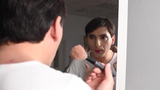 Ein homosexueller Mann schminkt sich vor einem Spiegel. Männliche Transgender. — Stockvideo