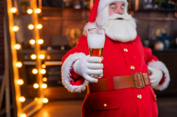 Santa Claus pije pivo, zatímco sedí v koženém křesle — Stock fotografie
