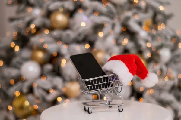 Smartphone avec écran noir dans un chariot. Achats en ligne de cadeaux de Noël. — Photo