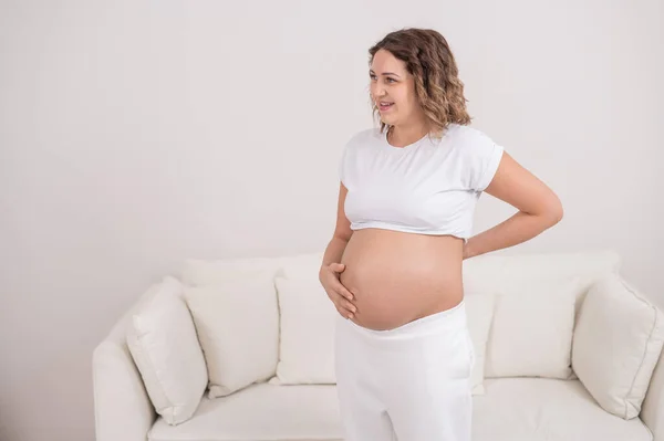 Беременная женщина держит живот и поясницу.. — стоковое фото