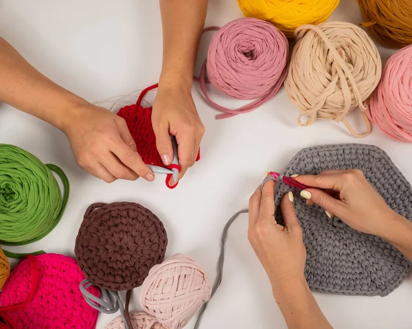 Top view of female hands with knitting on a white table. Two women are knitting baskets of cotton yarn. — Stock Photo, Image