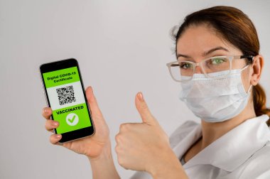 Doktor aşı öneriyor ve QR kodlu bir akıllı telefon tutuyor..