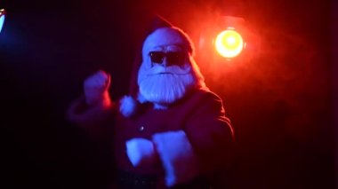 Güneş gözlüklü Noel Baba karanlıkta dans ediyor. Mutlu Noeller..