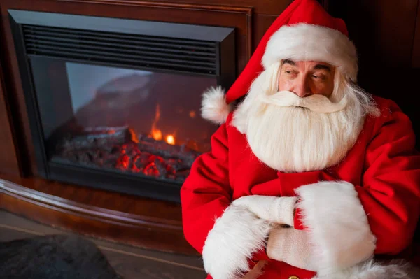 Porträt des Weihnachtsmannes, der zu Weihnachten am Kamin sitzt — Stockfoto