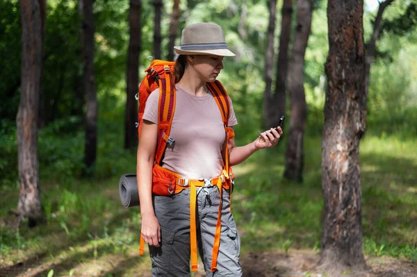 Молода біла жінка ходить пішки і використовує компас в лісі . — стокове фото