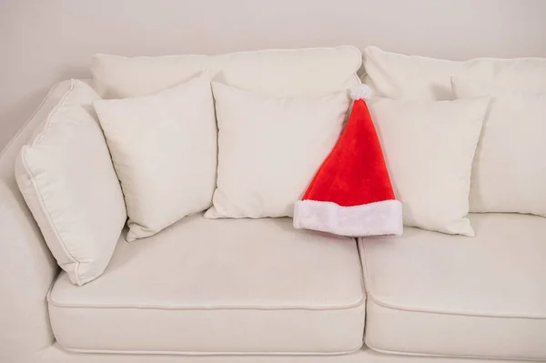 Weihnachtsmann-Hut auf weißem Sofa. — Stockfoto