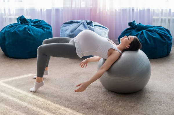 Hermosa mujer europea haciendo ejercicios de embarazo. La madre embarazada está haciendo ejercicios con una espada de fitness. Yoga para embarazadas . —  Fotos de Stock