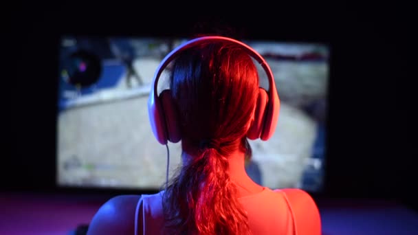 Vista trasera de una mujer caucásica jugando un juego de ordenador en luz de neón en la oscuridad. — Vídeos de Stock