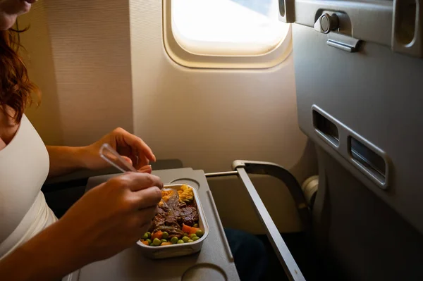 Mujer caucásica volando en clase económica y almorzando en una bandeja a bordo del avión. — Foto de Stock