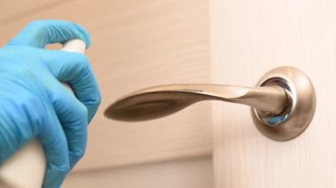 Kadın kapı kolunu dezenfekte eder..