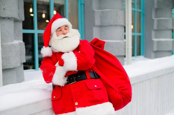 Тщательный Санта Клаус зимой прислоняется к фасаду дома — стоковое фото