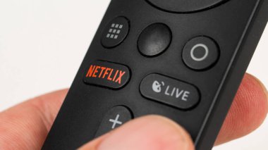 Rusya, Novosibirsk 10.11.2021: Beyaz bir masanın üzerinde netflix tuşu ile siyah bir uzaktan kumanda tutan bir adama yakın çekim.