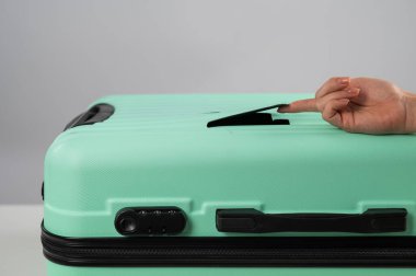 Bir kadın beyaz arka planda kırık bir bavulu gösteriyor. Uçuş sırasında hasarlı bagaj..