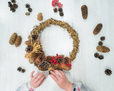 Kadın ellerinin Noel için çelenk yapmasının en üst görüntüsü. Yaşlı bir kadın yeni yıl için kendi elleriyle süsleme yapıyor.